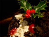 Kerstkaart: Drie blaadjes hulst met rode bessen bovenop de taart waar een munt in zit