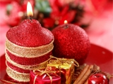Kerstkaart: Twee brandende rode kerstkaarsen met daarvoor twee kleine kerstpakjes