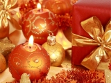 Kerstkaart: Twee brandende cremekleurige kerstkaarsen en een kerstbal naast een kerstcadeau