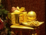 Kerstkaart: Tafeltje met daarop een goudkleurig kerstpakket en een goudkleurige kaars